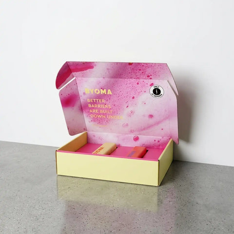 Image of Pink and yellow box with 'BYOMA' branding on a gray surface.